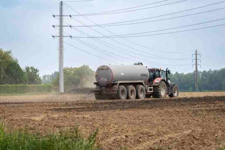 A tractor fertilizing a rural field with liquid manure for agriculture.