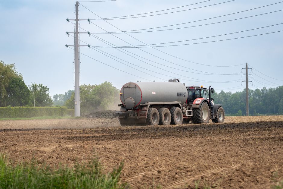 A tractor fertilizing a rural field with liquid manure for agriculture.