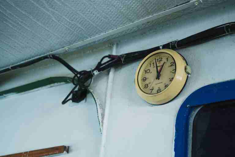 Yellow analog wall clock on industrial wall with exposed wiring and vintage feel.